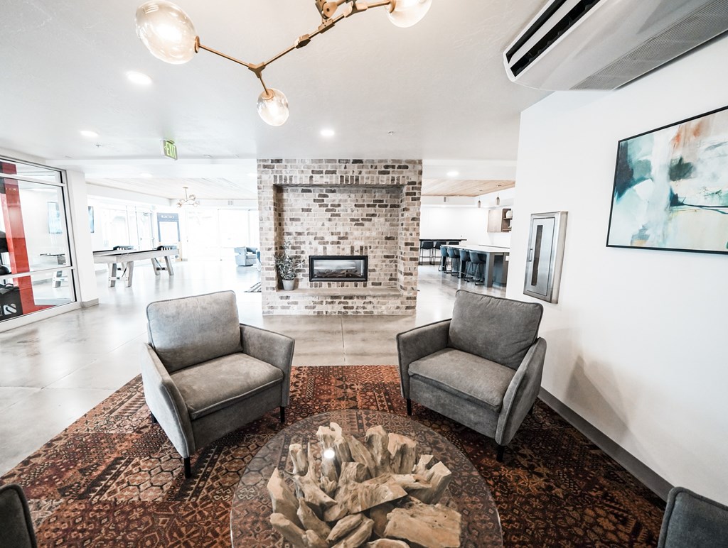 A living room with a fireplace and two grey chairs.