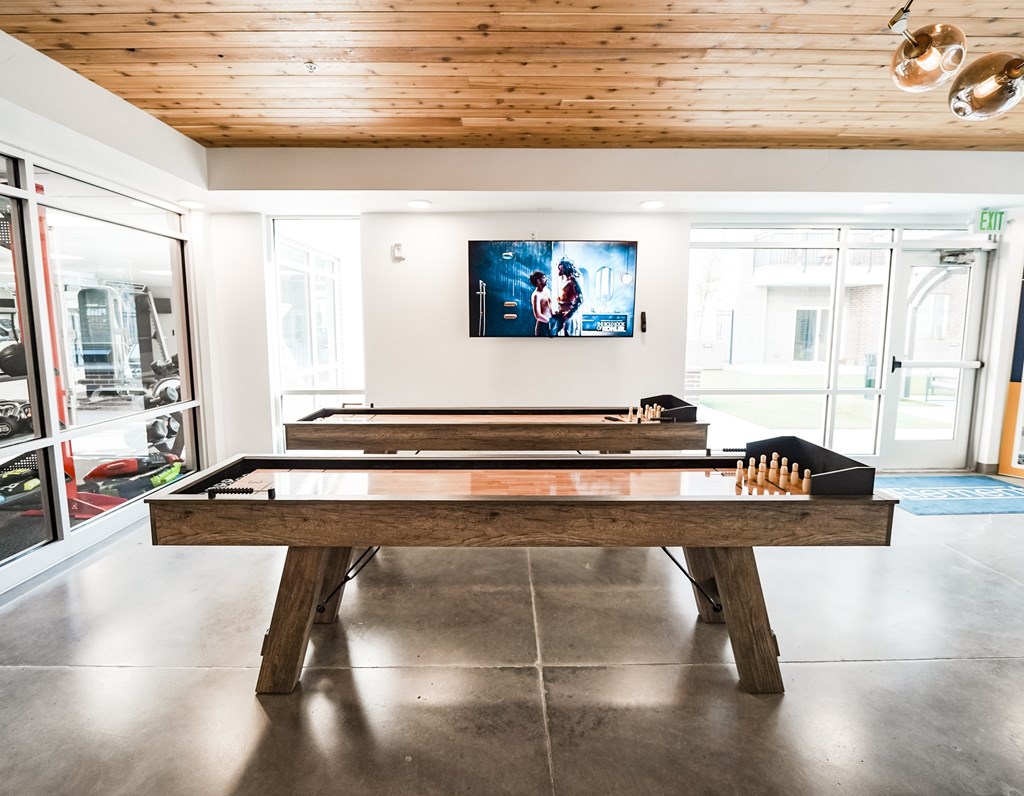 A billiard table in a room with a wooden ceiling and a TV mounted on the wall.