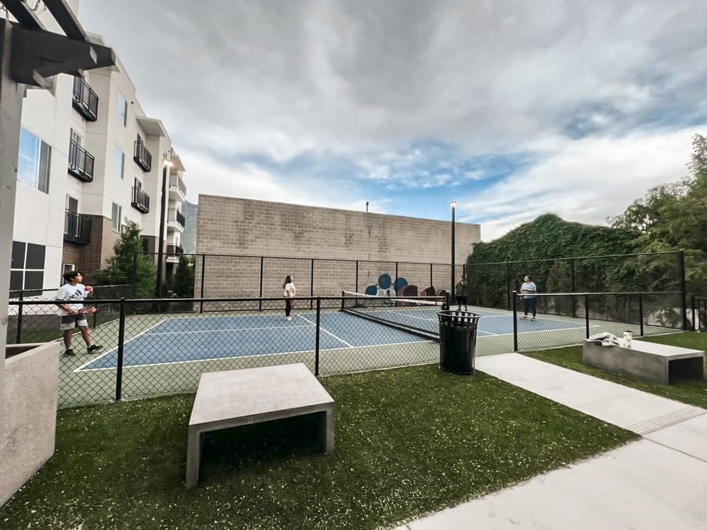 A tennis court surrounded by a fence and a bench.