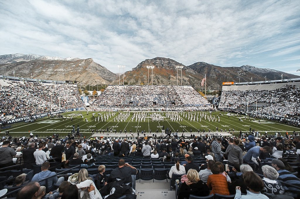 A large crowd of people are watching a marching band perform on a football field.
