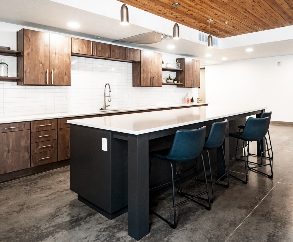 A modern kitchen with a black island and blue barstools.
