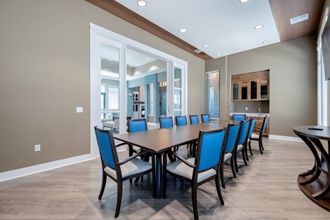 A conference room with a long table and blue chairs.