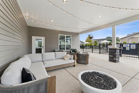 A modern outdoor living space with a grey sofa and a fire pit.