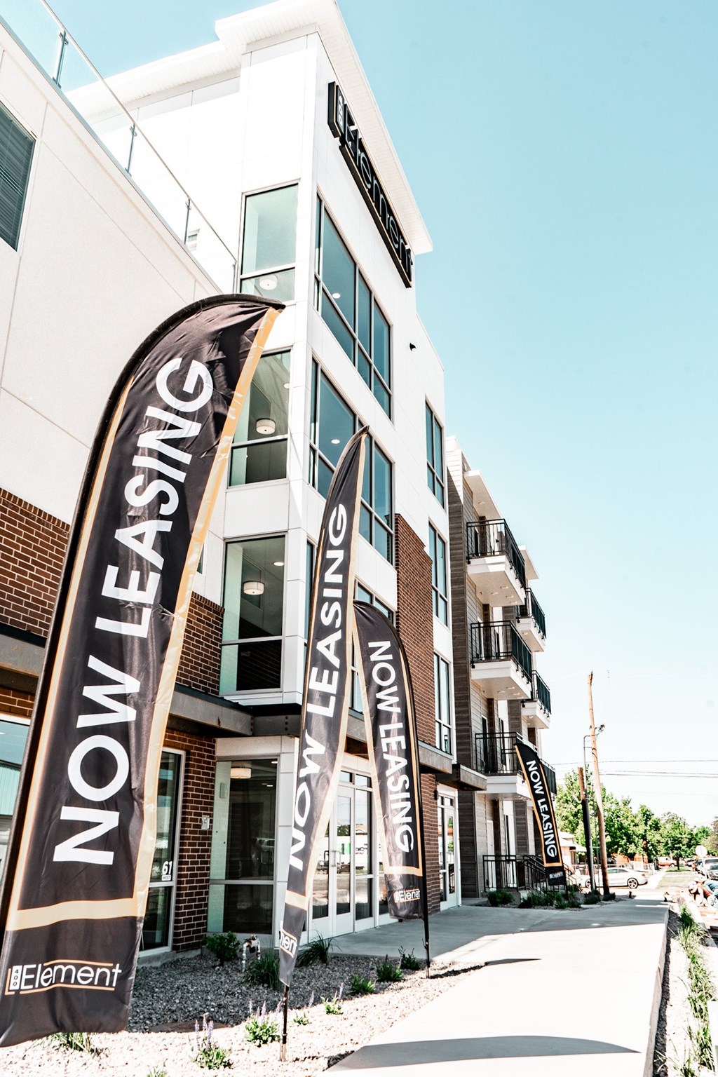 A building with a sign that says "Now Leasing" in front of it.