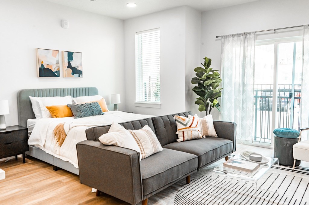 A modern bedroom with a large bed and a grey sofa.