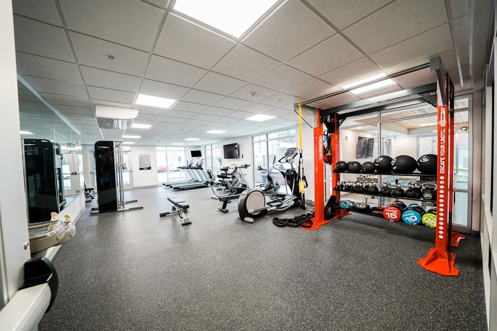 A gym with a variety of equipment including treadmills, weights, and exercise bikes.