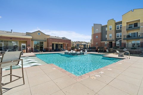 A pool surrounded by apartment buildings on a sunny day.