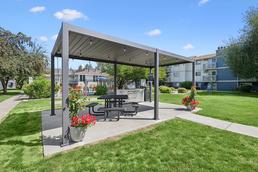 A picnic area with a table and chairs under a canopy.