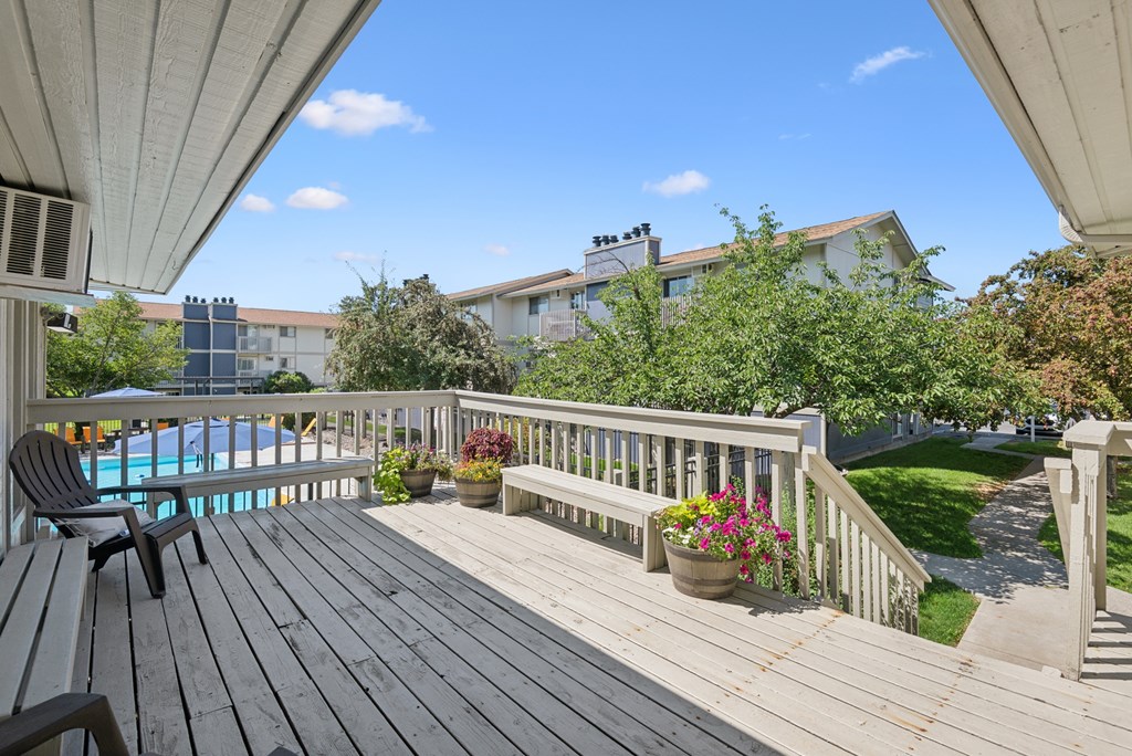 A wooden deck with a bench and a pool in the background.