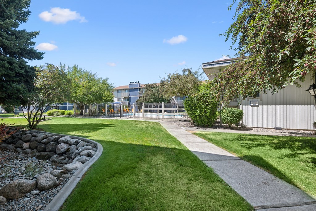 A well-maintained lawn with a stone pathway and a building in the background.