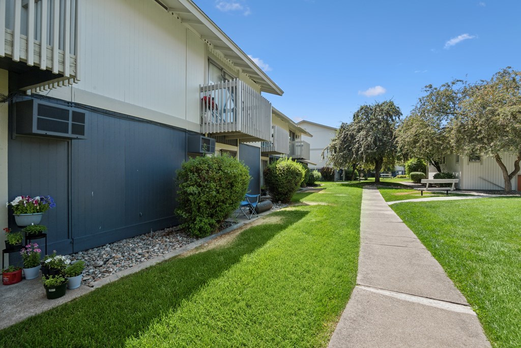 A walkway leads through a grassy area between two buildings.