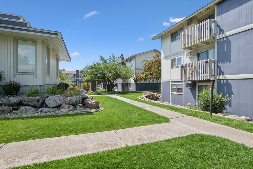 A sunny day in a residential area with apartment buildings and a well-kept lawn.