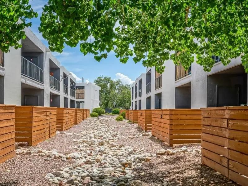 A row of modern buildings with wooden fences and gravel pathway.