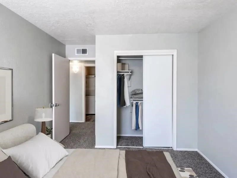 A bedroom with a bed, a lamp, and a closet.