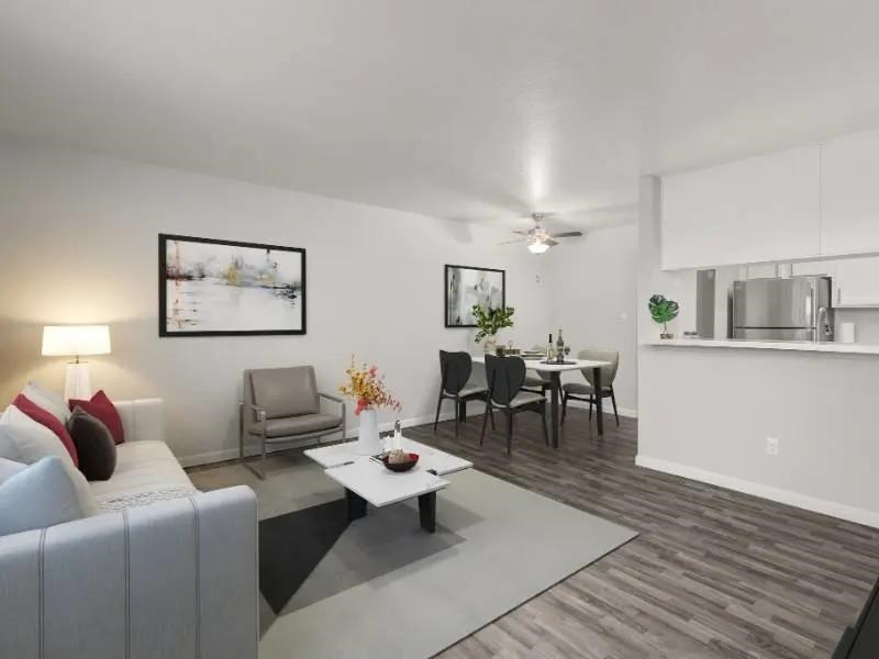 A living room with a grey sofa, a white coffee table, and a dining table with chairs.