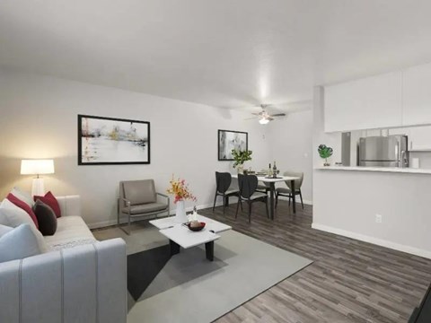 A living room with a grey sofa, a white coffee table, and a dining table with chairs.