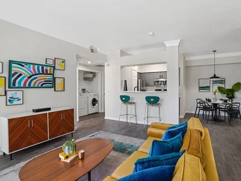 A living room with a yellow couch and a wooden coffee table.