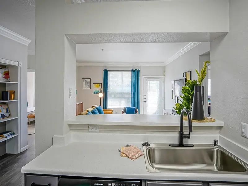 A kitchen with a white countertop and a stainless steel sink.