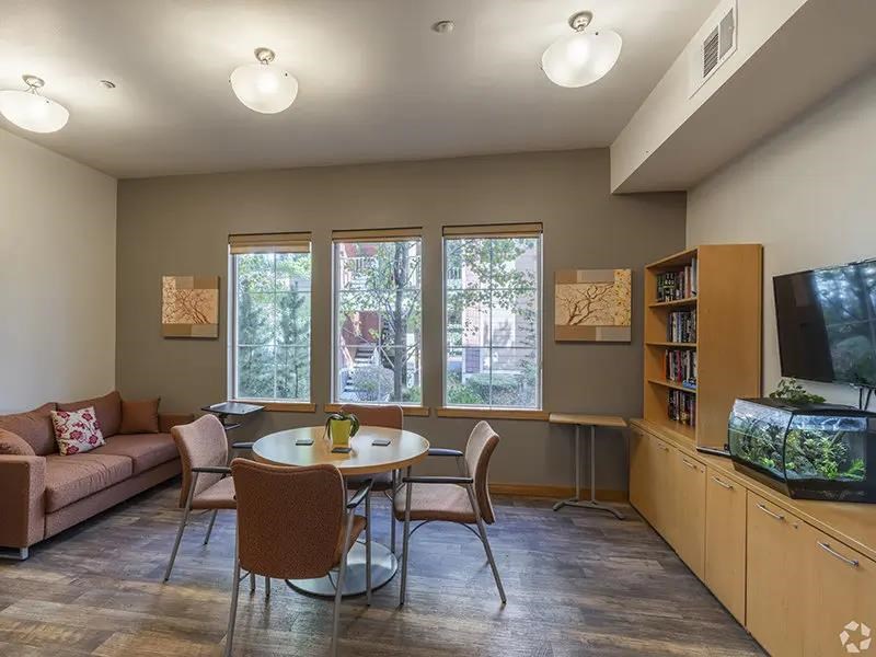 A living room with a couch, chairs, a table, and a television.