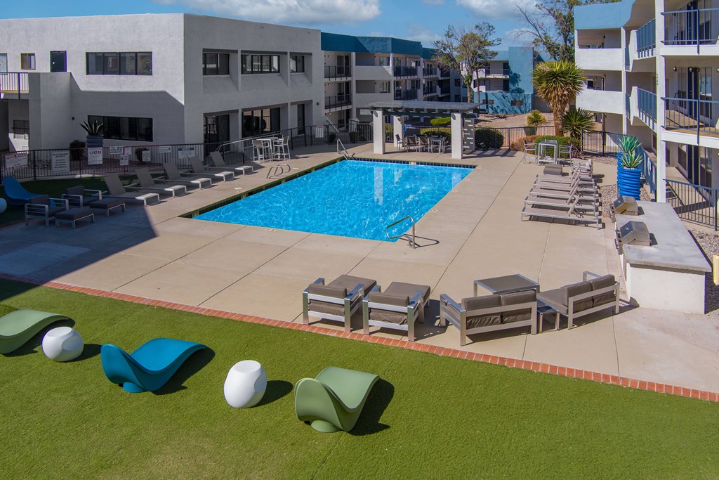 A swimming pool surrounded by lounge chairs and umbrellas.