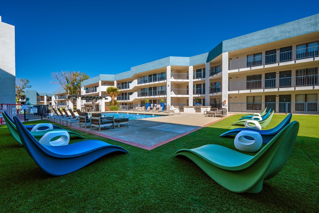 A modern building with a pool and two blue and green sculptures in front.