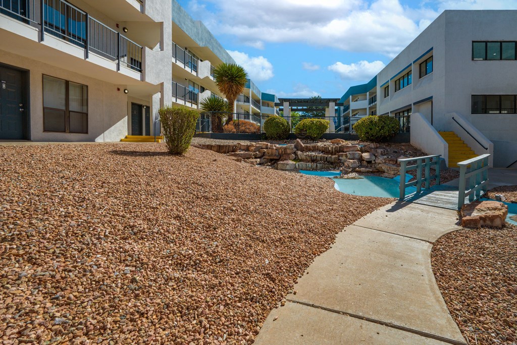 A building with a pool and a rocky ground.