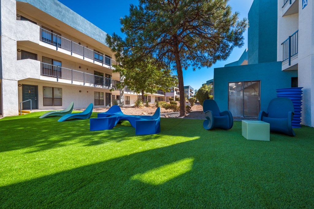 A playground area with a slide, swings, and a ball pit in front of a building.