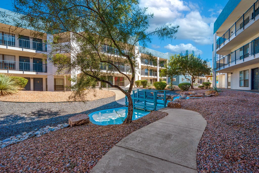 A small pool surrounded by a gravel area and a concrete walkway.