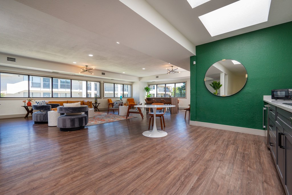 A modern kitchen with a green wall and wooden floors.