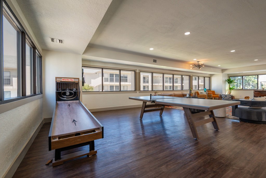 A shiny wooden table with a long bench in front of a window.