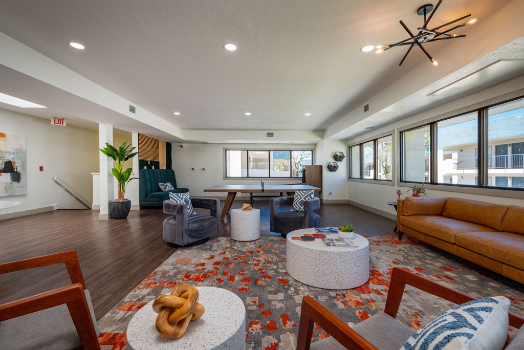 A living room with a brown couch and a rug with a pretzel on it.