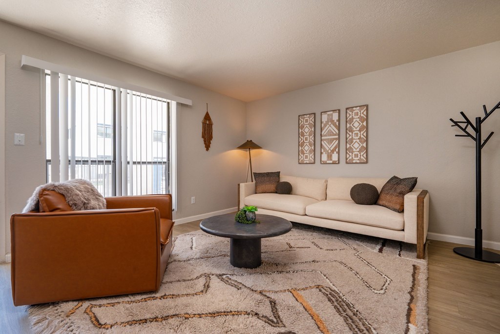 A living room with a white couch, a brown chair, and a black table.