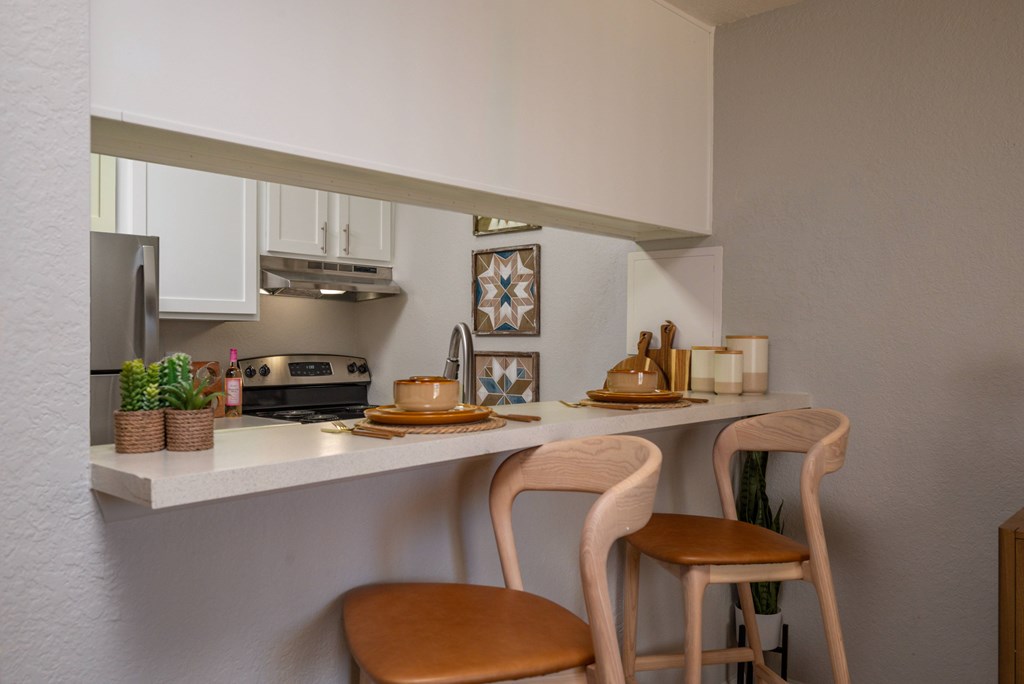 A kitchen with a white counter and two chairs.