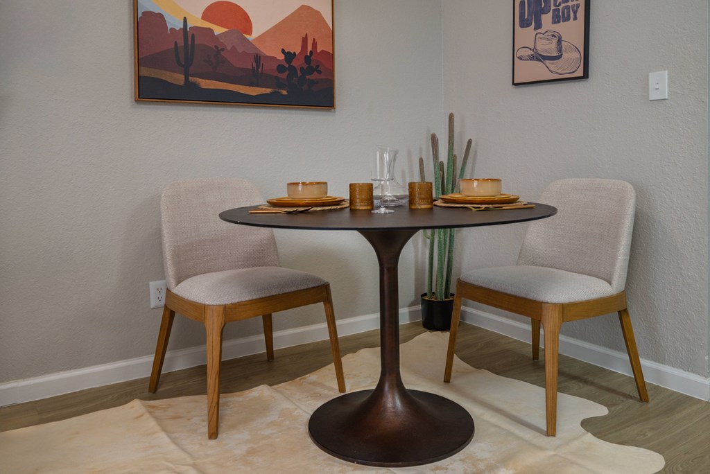 A table with two chairs and a painting on the wall.