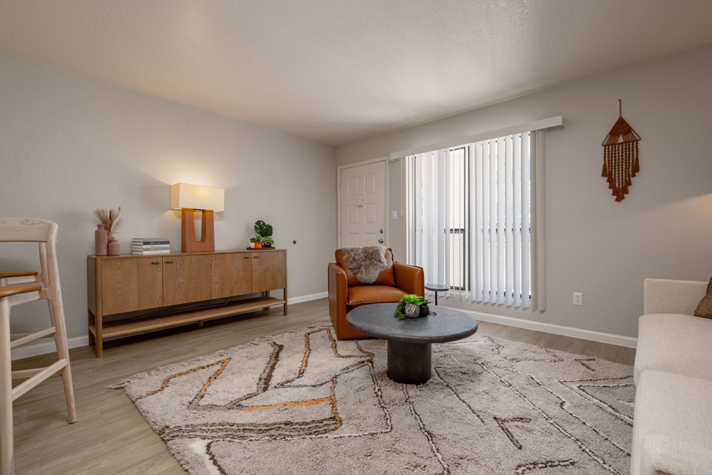 A living room with a rug, a wooden cabinet, a chair, and a table.