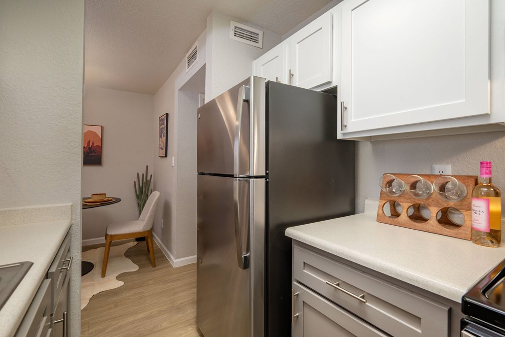 A kitchen with a stainless steel refrigerator and white cabinets.