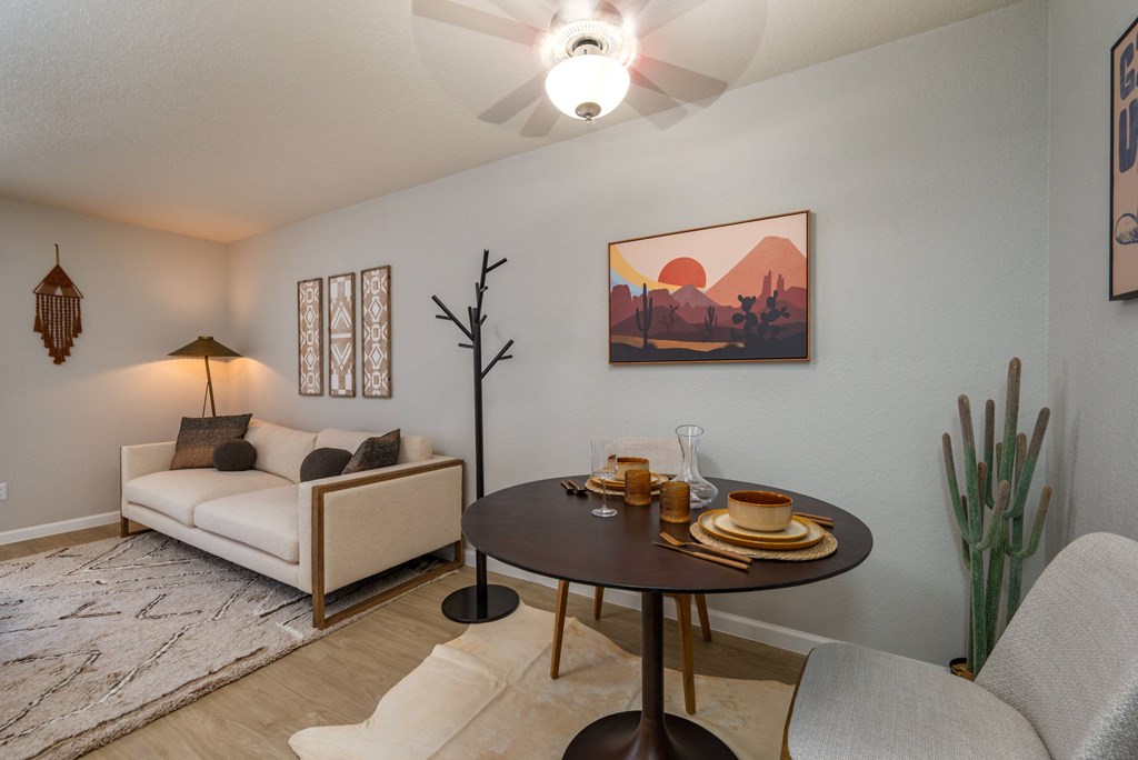 A living room with a white couch, a round table with plates on it, and a painting on the wall.