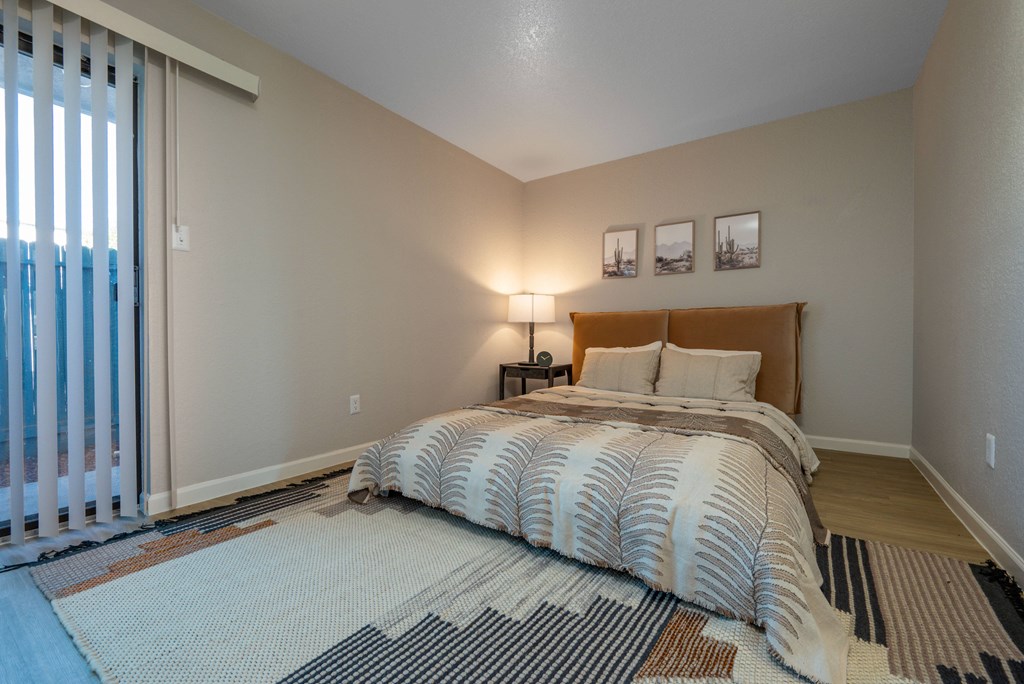 A bedroom with a bed, two lamps, and pictures on the wall.