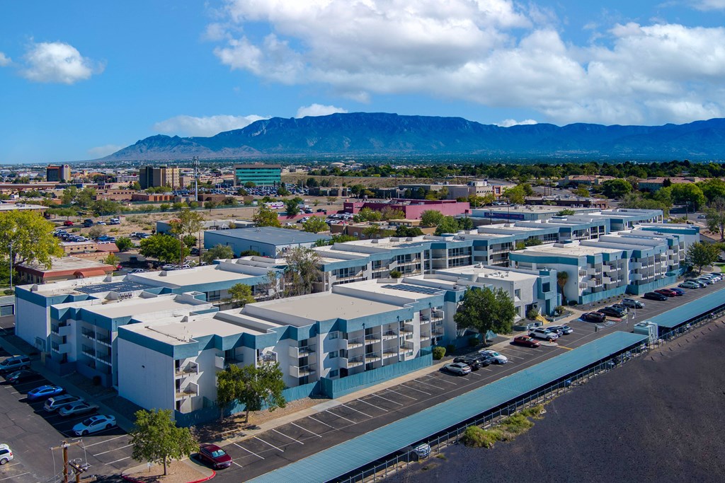 A large building complex with a parking lot in front and mountains in the background.