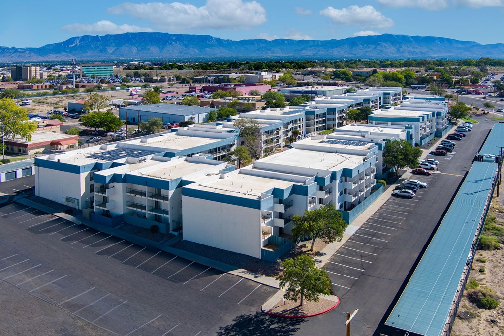 A parking lot in front of a building with a mountain in the background.