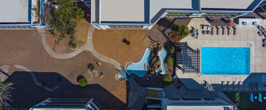 A pool area with a small waterfall and a hot tub.