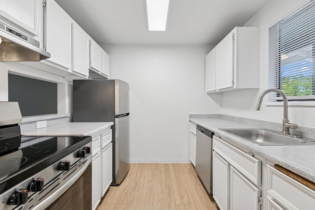 A modern kitchen with white cabinets and stainless steel appliances.