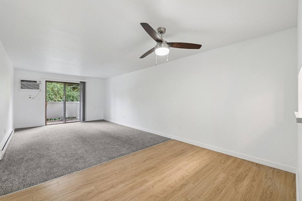 A room with a ceiling fan and a door leading to a balcony.