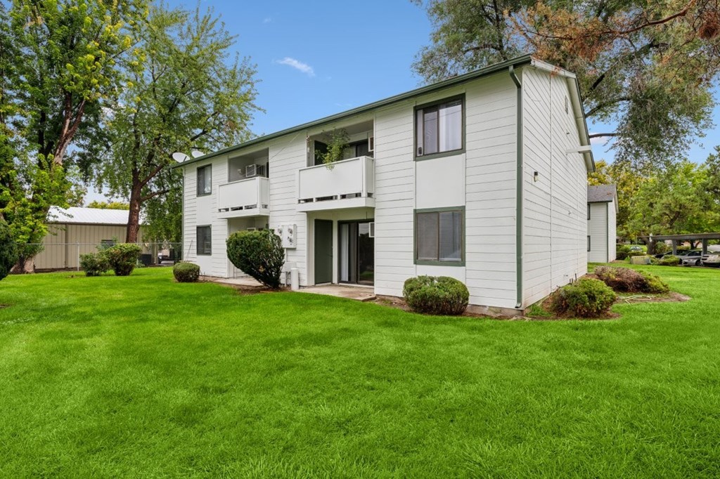 A white two-story apartment building with a green lawn in front.