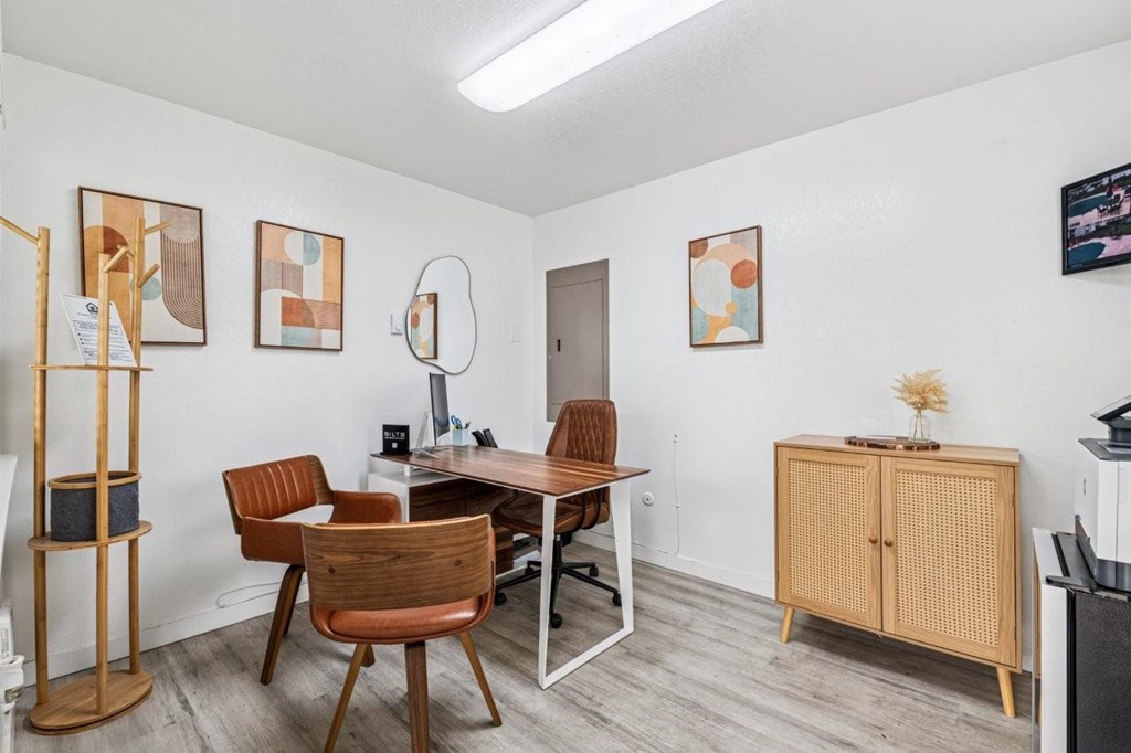 A room with a desk, chairs, and a cabinet.