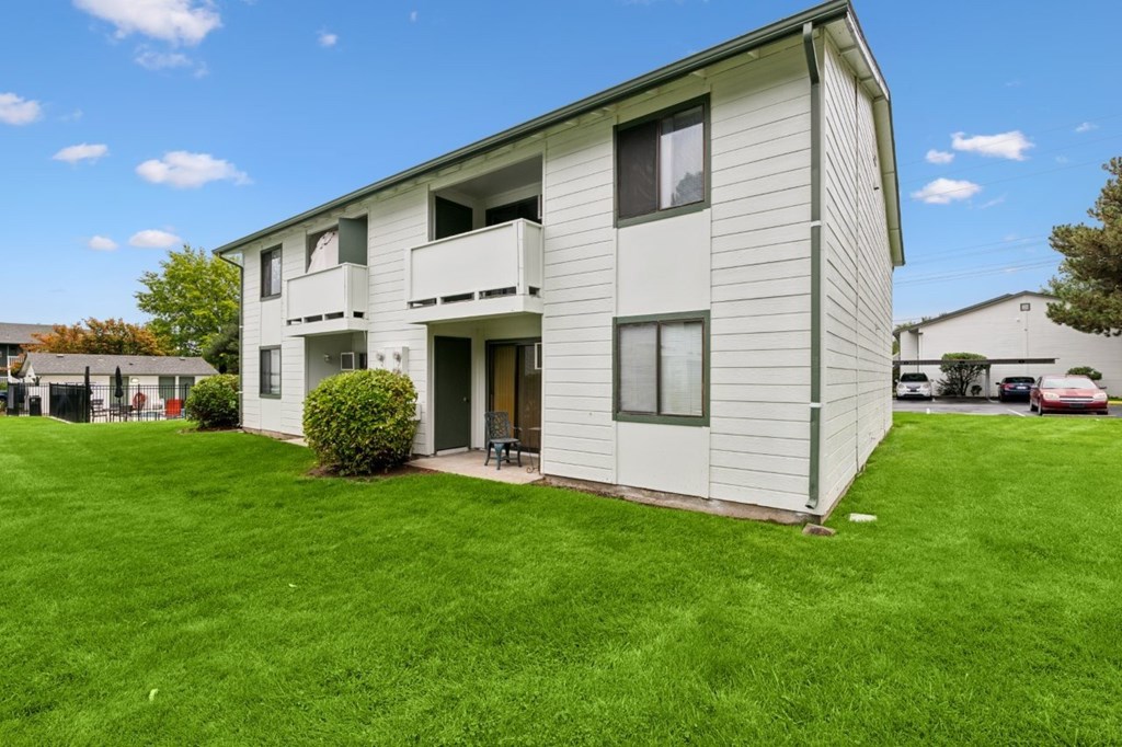 A white two-story apartment building with a green lawn in front.