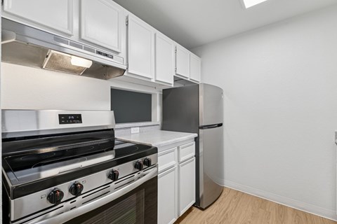 A modern kitchen with a stainless steel stove and white cabinets.