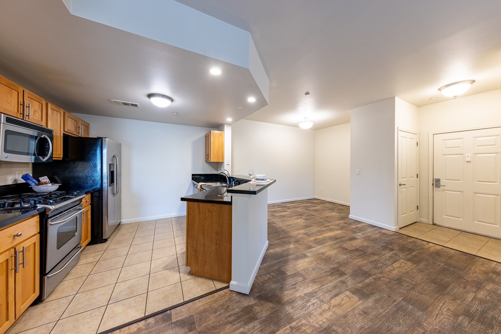 A kitchen with wooden cabinets and a black refrigerator.