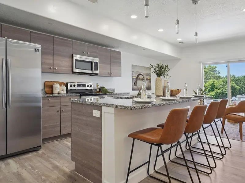 A kitchen with a refrigerator, microwave, oven, and sink.