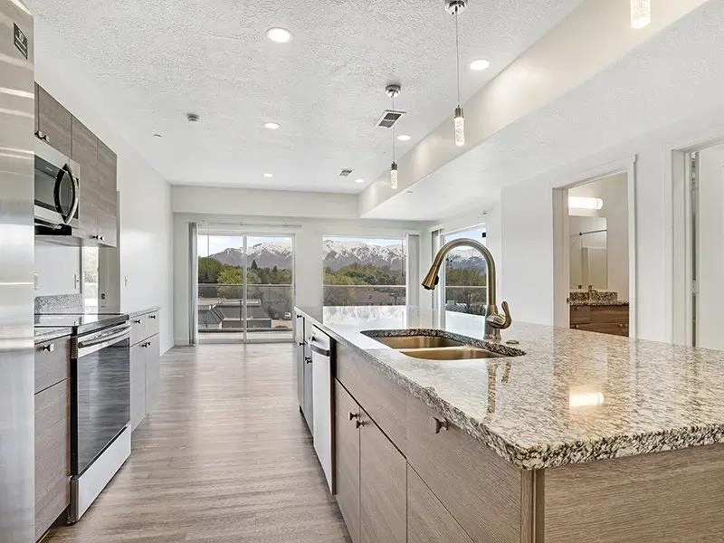 A modern kitchen with a marble countertop and a view of the mountains outside the window.